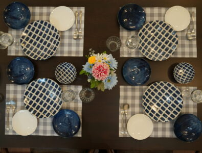 Elegant dining table setting at Ocean Villa Tokunoshima with blue and white patterned dishes, crystal glasses, and fresh flower centerpiece.