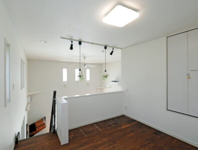 Modern loft area at Ocean Villa Tokunoshima with white minimalist design, track lighting, hanging planters, and rich dark wood flooring.