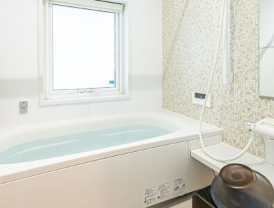Modern bathroom at Canal Villa Otaru with deep soaking tub, glass shower enclosure, mosaic tile accent wall, and natural light window.